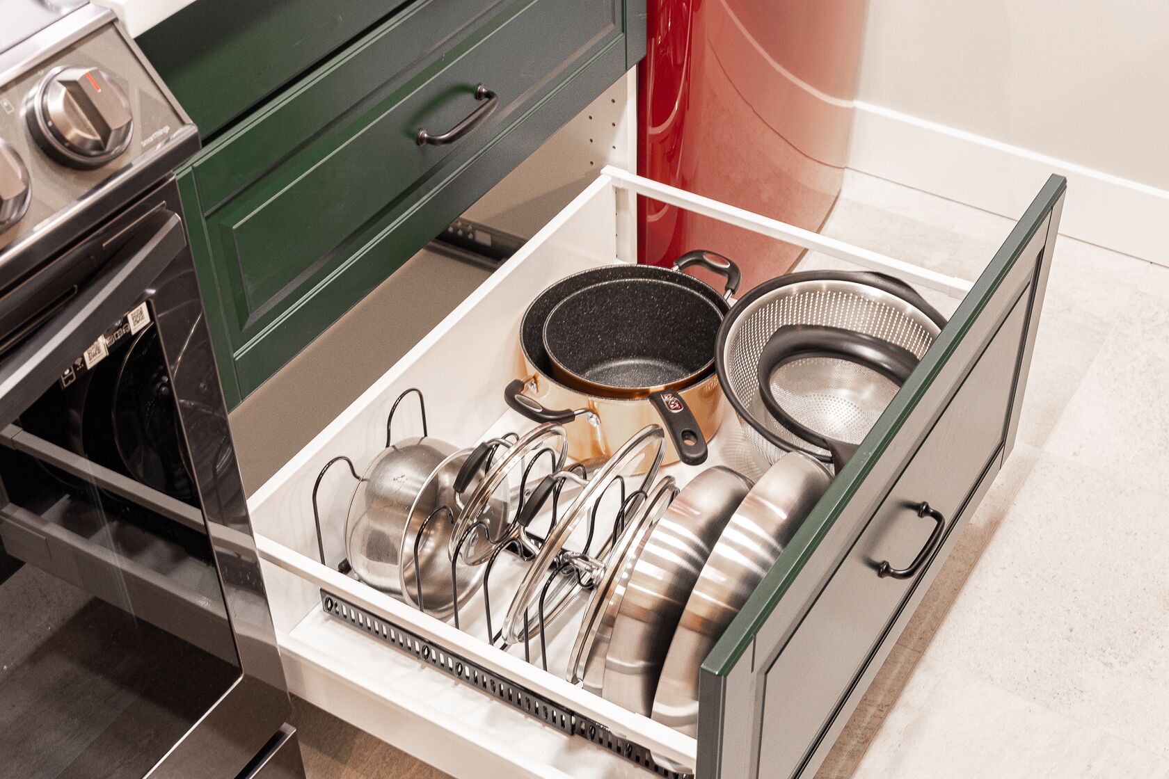Un cajón de cocina con varias ollas, sartenes y utensilios.