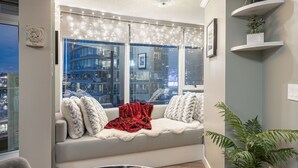 Un coin salon confortable avec vue sur la ville, un nid décoratif et une couverture rouge.