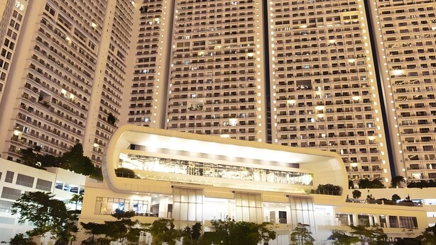 Un immeuble de grande hauteur doté de nombreux balcons et d’une structure moderne et incurvée à sa base.