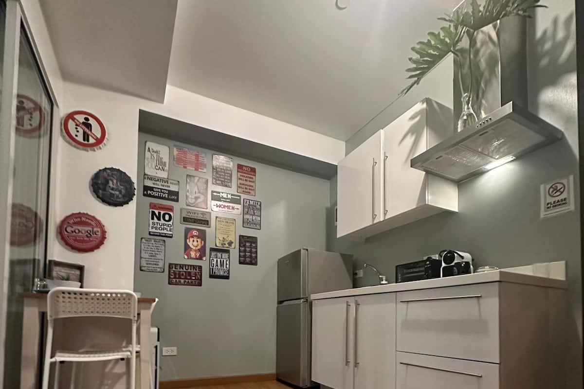 A compact kitchen with white cabinets, a refrigerator, and a dining area with a chair and table.