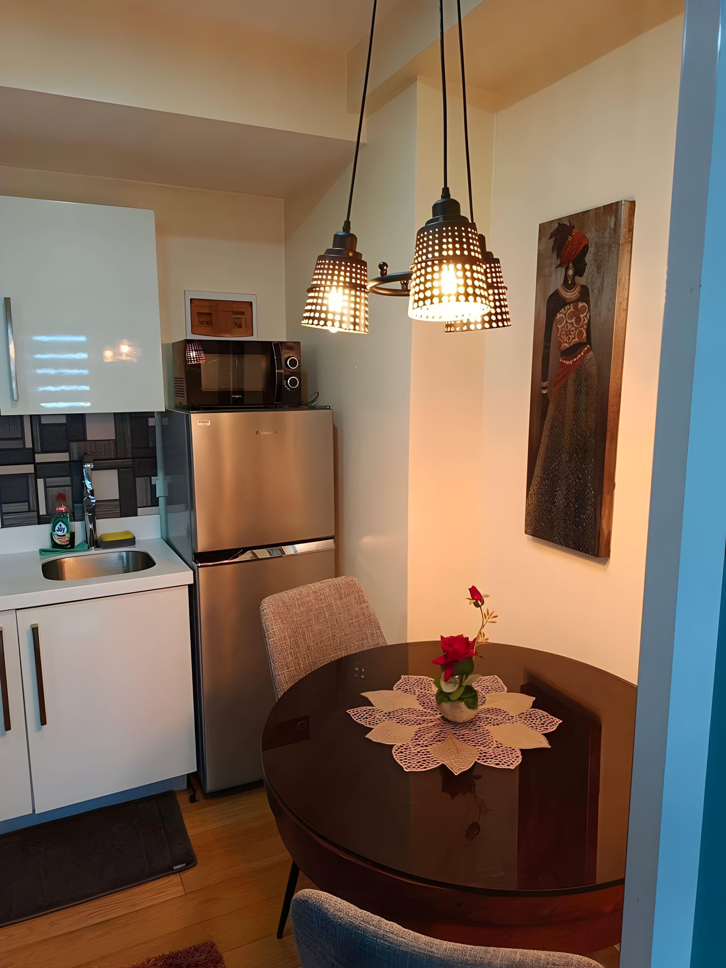 A modern kitchen with a refrigerator, microwave, and a dining table with a vase of flowers.
