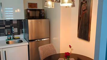 A modern kitchen with a refrigerator, microwave, and a dining table with a vase of flowers.