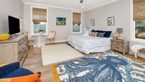 Una camera da letto con un letto, comodini, una ventola a soffitto e opere d'arte alle pareti.