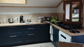 A modern kitchen with dark cabinets, a countertop, a sink, and a window.