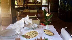 Uma mesa de jantar posta com pratos de comida, copos e um jarro de chá.