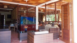 Quarto espaçoso com um grande aquário, móveis de vime e teto de madeira.