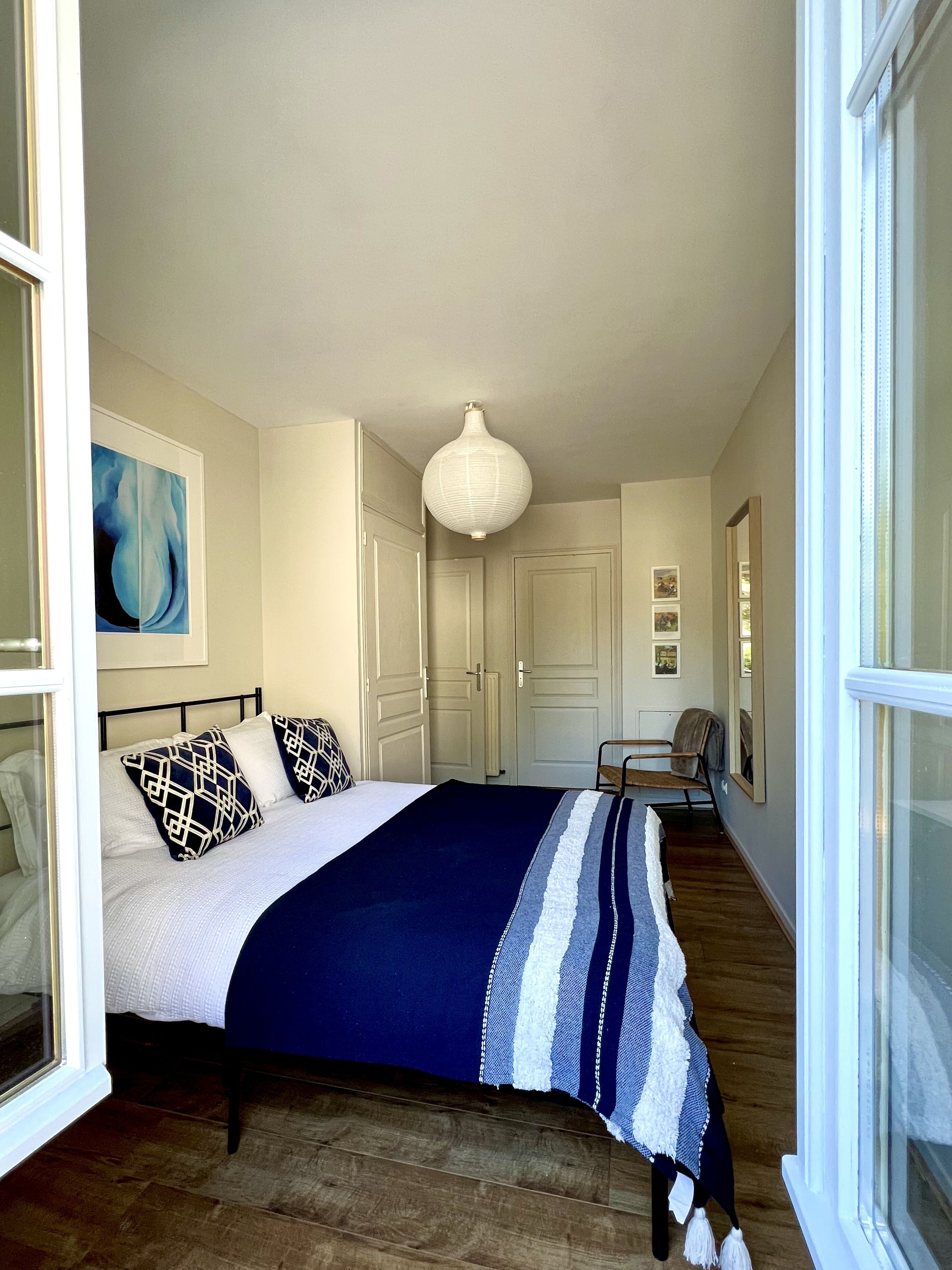 Une chambre à coucher avec un lit, un luminaire suspendu, une chaise et une porte.