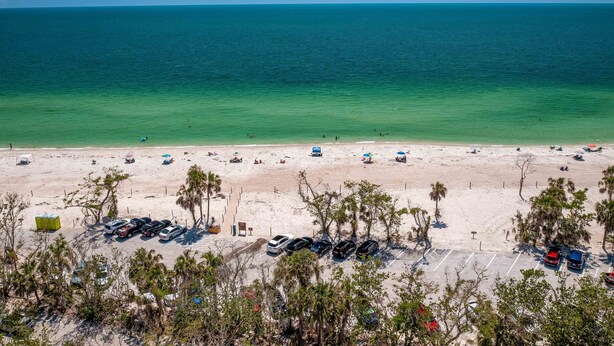 A beach with a parking lot and a view of the ocean. - 8th Floor Oceanview! Large Balcony ~ Steps to Vanderbilt Beach (Naples)