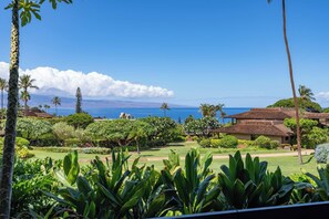 A tropical resort with a view of the ocean, lush greenery, and a traditional building with a thatched roof. - 3BR Ka’anapali Retreat | Ocean Views, Gorgeous renovation, Walk to Beach (Lahaina)