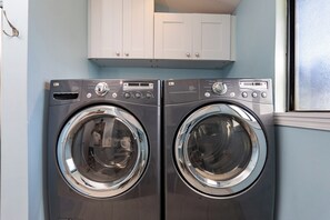 A laundry room with two front-loading washing machines and a white cabinet above them.