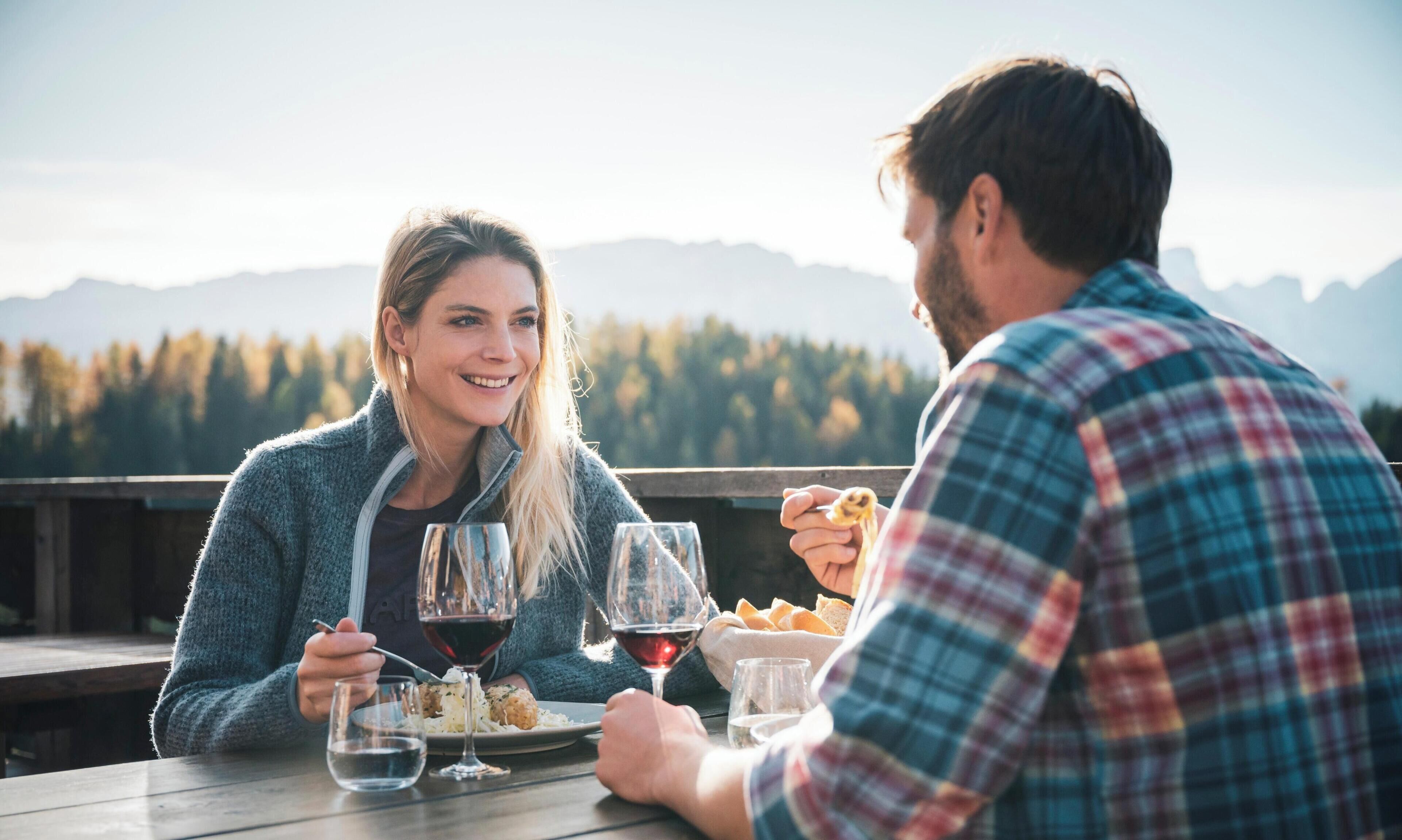 Two people dining outdoors with a mountain view in the background.