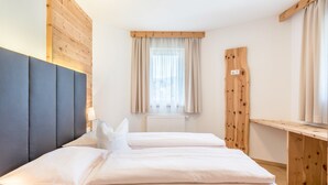 A hotel room with a bed, a headboard, a window with curtains, and a wooden wall panel. - Apartments Marialisa Superior 'Apt Tulpe' with Mountain View, Whirlpool & Wi-Fi (Chiusa)
