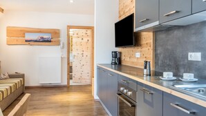 A modern kitchen with wooden accents, a flat-screen TV, and a built-in oven. - Apartments Marialisa Superior 'Apt Tulpe' with Mountain View, Whirlpool & Wi-Fi (Chiusa)