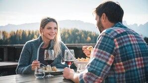 Two people dining outdoors with a mountain view in the background. - Apartments Marialisa Superior 'Apt Orchidee' with Mountain View, Whirlpool & Wi-Fi (Chiusa)