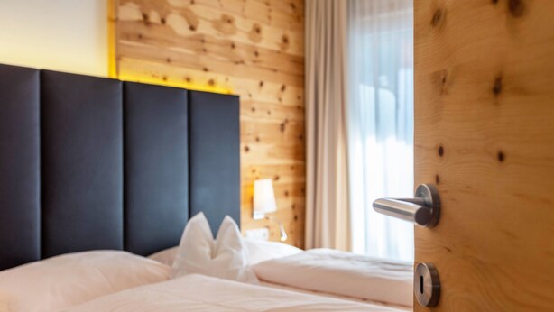 A bed with white linens, a dark headboard, and a wooden wall with a window. - Apartments Marialisa Superior 'Apt Orchidee' with Mountain View, Whirlpool & Wi-Fi (Chiusa)