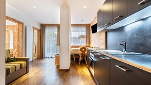 A modern kitchen with wooden flooring, a dining area with a table and chairs, and a sofa. - Apartments Marialisa Superior 'Apt Orchidee' with Mountain View, Whirlpool & Wi-Fi (Chiusa)