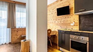 A modern kitchen with wooden paneling, a flat-screen TV, and built-in appliances. - Apartments Marialisa Superior 'Apt Orchidee' with Mountain View, Whirlpool & Wi-Fi (Chiusa)