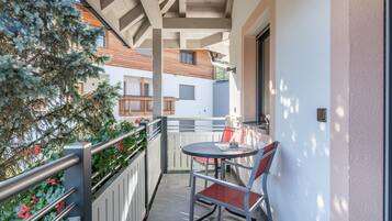 Varanda com mesa e cadeira, corrimão e vista para edifícios próximos.