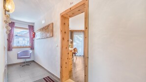 A hallway with a wooden door, a chair, a small table, and a window with curtains. - Apartments Marialisa Superior 'Apt Rose' with Mountain View, Whirlpool & Wi-Fi (Chiusa)