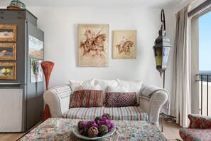 Ein Wohnzimmer mit einer Couch, einem Tisch mit Dekoration und Kunstwerken an der Wand.