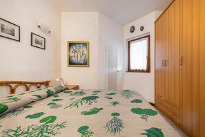 A bedroom with a bed, a wardrobe, a door, and a wall with framed pictures.