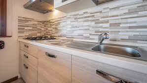 A modern kitchen with a gas stove, stainless steel sink, and a hutch with drawers. - Holiday Home 'Bianca' with Sea View, Private Terrace and Air Conditioning (Costa Rei)