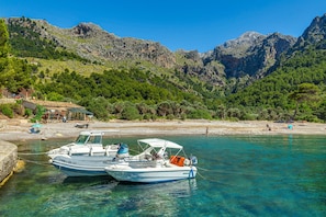 Two boats docked at a waterfront with a mountainous backdrop.