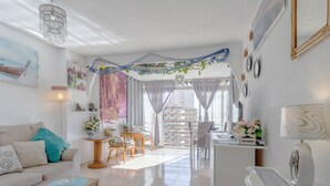 En moderne stue med sofa, sofabord, spiseområde og køkken.