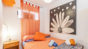 A bedroom with a bed, orange curtains, a wall art piece, and a bedside table. - Apartment Moby Dick with Sea View, Shared Pool & Wi-Fi (Benidorm)