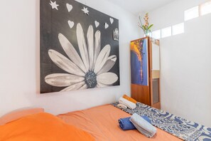 A room with a bed, a large flower painting, a wardrobe, and a mirror.