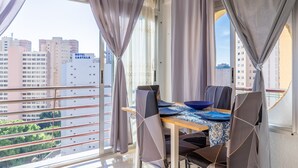 A dining area with a table, chairs, and a view of buildings outside. - Apartment Moby Dick with Sea View, Shared Pool & Wi-Fi (Benidorm)