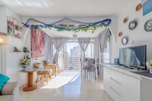 A modern living space with a balcony, dining area, and a TV.
