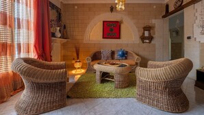 A living room with wicker furniture, a fireplace, and a red wall decoration.