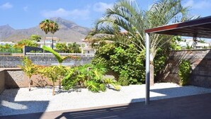 Eine Terrasse mit einer Pergola, Palmen und Blick auf einen Berg.