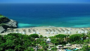 Ein Strandresort mit Pool, Liegestühlen und Sonnenschirmen.