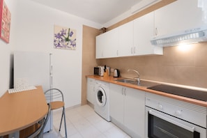 Une cuisine compacte équipée d’un lave-linge, d’un four à micro-ondes, d’un évier et d’une cuisinière.