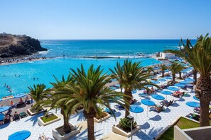 A resort with a large pool, palm trees, and beach access.