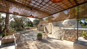 An outdoor patio with stone walls, a pergola, wicker furniture, and potted plants. - Holiday Home Trullo with Shared Pool, Shared Garden & Terrace (Ostuni)