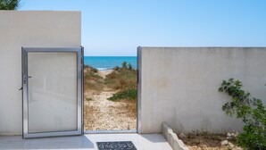 Una obertura que dona a un camí de sorra amb vista al mar.