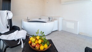 Habitació d'spa amb banyera d'hidromassatge, una cadira relaxant i un plat de fruita.