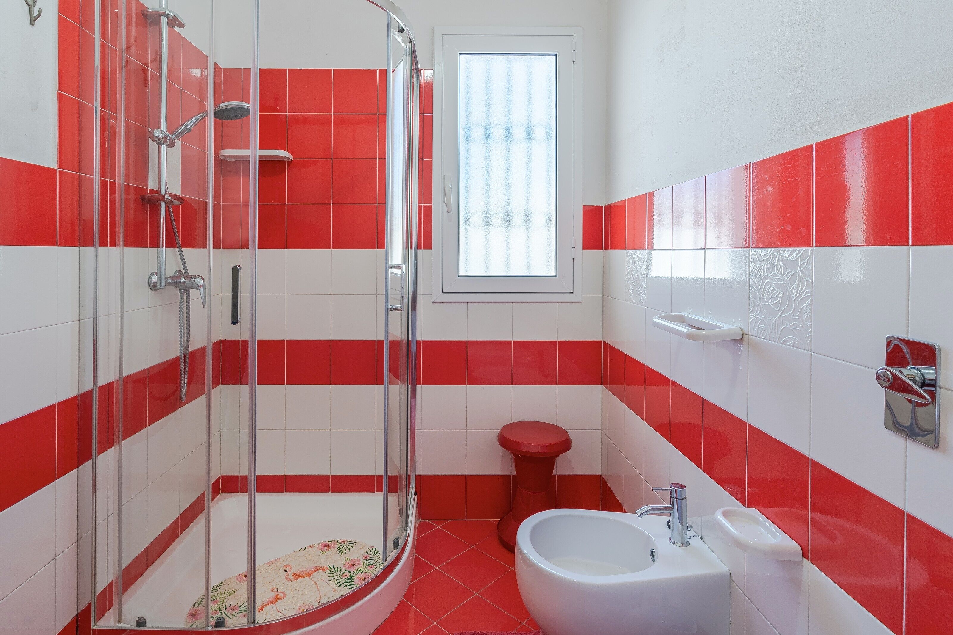 A bathroom with a shower, toilet, sink, and window.