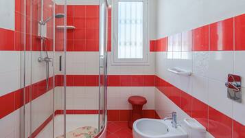 A bathroom with a shower, toilet, sink, and window.