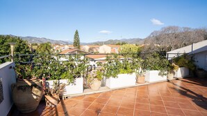 A rooftop terrace with potted plants, a large terracotta pot, and a view of houses and mountains. - Holiday Home "Giugiò" with Mountain View, Terrace, and Air Conditioning (Giardini Naxos)