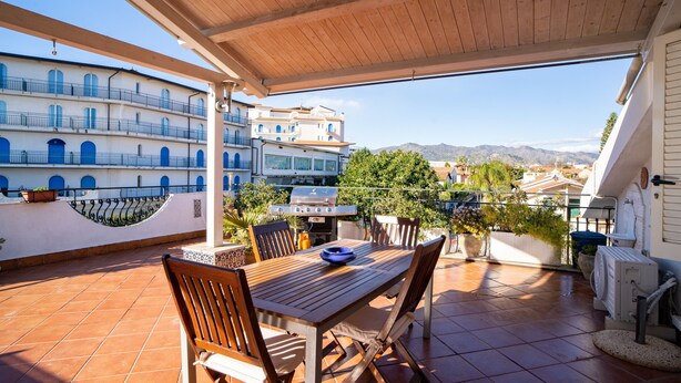 An outdoor patio with a wooden table and chairs, a grill, and potted plants. - Holiday Home "Giugiò" with Mountain View, Terrace, and Air Conditioning (Giardini Naxos)