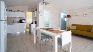 A modern kitchen with white cabinets, a dining table with chairs, a yellow sofa, and a red floor lamp. - Holiday Home "Giugiò" with Mountain View, Terrace, and Air Conditioning (Giardini Naxos)