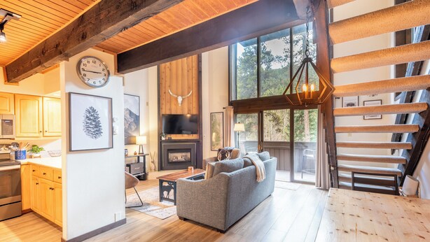 A spacious living area with a fireplace, a large window, and a wooden ceiling. - Ski in/Walk out Center Village condo, Excellent location, Mountain View (copper mountain)