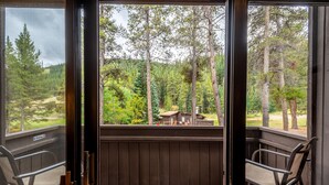 A wooden deck with a view of a forest and a cabin. - Ski in/Walk out Center Village condo, Excellent location, Mountain View (copper mountain)
