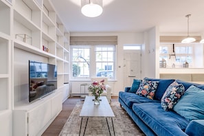Relax in this stylish living room with a large flat-screen TV, plush sofa, and beautiful floral accents.