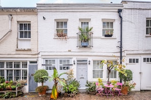 Stylish townhouse with a charming exterior, featuring a traditional front door and a cozy balcony with potted plants.