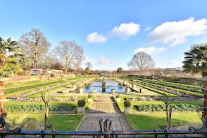 Stunning garden with a central water feature, surrounded by neatly trimmed hedges and lush shrubs.